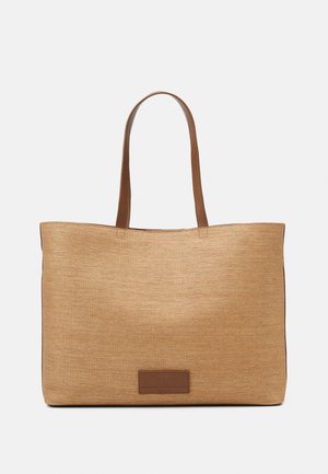 Grand sac cabas rectangulaire beige avec corps en tissu texturé, deux anses en cuir marron et une petite étiquette rectangulaire en cuir à l'avant.