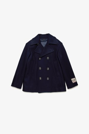 Navy wool peacoat with double-breasted design, large lapels, and black buttons. Features two side pockets and a tag on the sleeve.