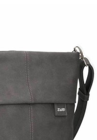 Bolso de hombro de cuero gris con parte superior plegada, costuras prominentes, correa ajustable y una pequeña etiqueta con el logo. Textura suave con un diseño elegante.