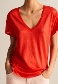 Rød V-hals T-shirt med korte ærmer, let stof, subtile teksturer, afslappet pasform og sideslids for ekstra komfort og stil.