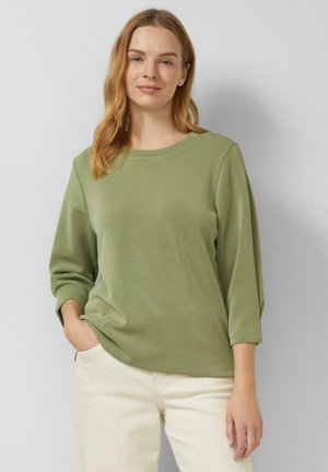 Langärmliges Olivgrünes Hemd mit Rundhalsausschnitt, weicher Textur und lockerer Passform, kombiniert mit hellfarbenen Hosen.