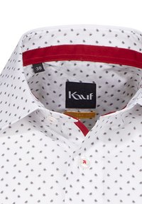 Weißes Hemd mit einem kleinen, repetitiven Muster in Marineblau. Der Innenteil des Kragens hat einen roten Akzent. Markenetikett: Kauff, Größe 38.