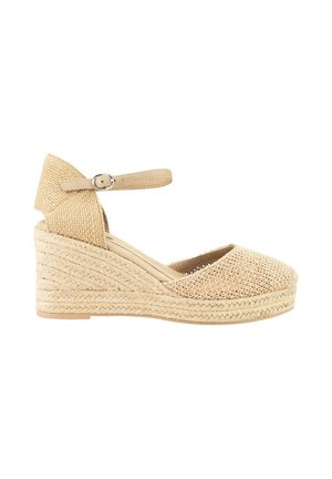 Espadrille de cuña en beige con parte superior de lona tejida y suela de yute texturizada. Cuenta con una correa en el tobillo con una hebilla plateada.