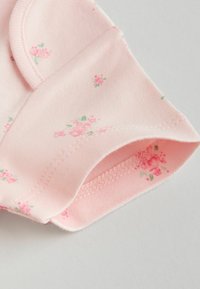 Roosa puuvillane kangas väikeste lillemustritega, millel on pehme tekstuur ja kõverad ääred. Sisaldab õrna õmblust ja istuvat varrukakujundust.