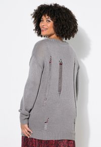 Übergroßer grauer Strickpullover mit gerippten Bündchen und Saum. Besitzt absichtliche Abschürfungen mit Ausschnitten entlang des Rückens für eine strukturierte Optik.
