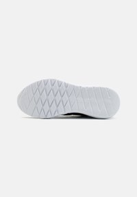 Semelle en caoutchouc blanc d'une chaussure de sport avec un motif géométrique de losanges et de lignes, vue par le dessous.