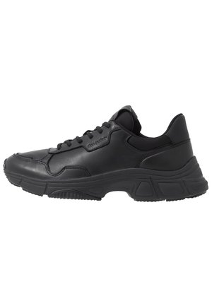Black low-top leather sneaker with thick rubber sole, lace-up front, and subtle Calvin Klein logo on side.