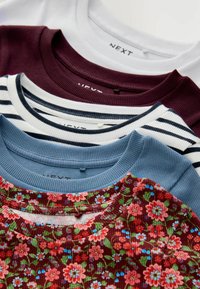 Stapel von gerippten Rundhals-Shirts in Weiß, burgunderrot, marineblauen Streifen, Blau und rotem Blumenmuster mit grünen Blättern.