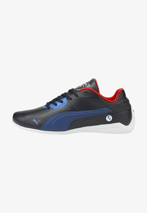 La scarpa sintetica nera presenta dettagli blu e un colletto rosso, con una suola bianca e pannelli testurizzati. Sono visibili il logo Puma e il badge BMW.