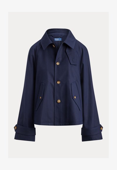 Námornícky modrá bunda z ľahkej tkaniny, s hrotovým golierom, zlatými gombíkmi, dvoma prednými vreckami a vyhrnutými rukávmi.