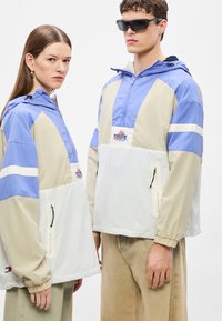 Könnyű, színblokkolt anorákok kék, bézs és fehér színekben. Állítható kapucni, cipzárak és logópatch jellemzi őket. Sima textúrájú, sportos kialakítású.