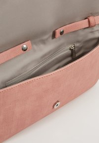 Różowa torba tekstylna od wewnątrz z miękką podszewką, z kieszonką na zamek błyskawiczny i zapięciem na zatrzask; subtelna tekstura i elegancki design.