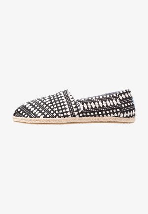 Espadrille à motifs noir et blanc avec une tige en textile tissé, bout arrondi et semelle en jute tressé, présentant un design à enfiler.