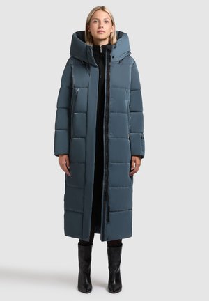 Abrigo largo y acolchado en azul apagado con un cuello alto y una gran capucha. Presenta un cierre de cremallera y bolsillos laterales. Textura suave y brillante.