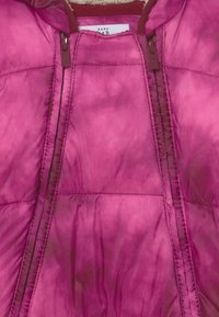 Roze donsjack met een gladde textuur, voorritsen en gestikte details. De binnenvoering is in een contrasterende bordeauxkleur.