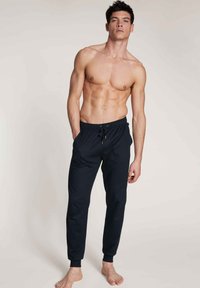 Zwarte joggingsbroek met een elastische tailleband en trekkoord, taps toelopende benen en ribbelmanszetten, gemaakt van een zachte, lichtgewicht stof.