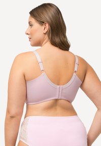 Vaaleanpunainen rintaliivi, joka on valmistettu sileästä kankaasta. Varustettu säädettävillä olkahihnoilla, hakaskiinnityksellä selässä ja hapsureunoilla. Yhdistetty yhteensopiviin pikkareihin.