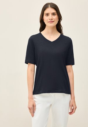 Navyblauwe T-shirt met korte mouwen en V-hals, gemaakt van een lichtgewicht, gestructureerde stof. Rechte, ontspannen pasvorm, gedragen met off-white broeken.