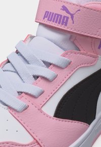 Ροζ και λευκό αθλητικό παπούτσι Puma με λευκά κορδόνια, μαύρη πλευρική ρίγα και ροζ λουράκι με βέλκρο που φέρει μωβ λογότυπο Puma.