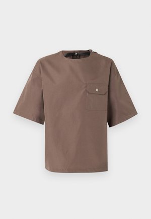 Braunes Kurzarmhemd mit Rundhalsausschnitt und einer Klapptasche auf der linken Brust, präsentiert vor weißem Hintergrund.