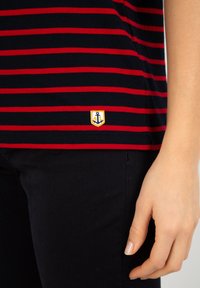 Marineblauw en rode gestreepte t-shirt met een klein geborduurd ankerpatch op de zoom, gemaakt van zachte katoenstof, met een klassieke uitstraling.