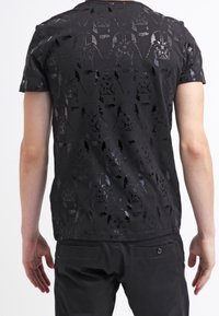 Černé tričko s texturovaným vzorem stylizovaných tváří Darth Vadera, s kulatým výstřihem a krátkými rukávy. Hladký materiál.