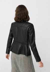 Černá kožená bunda s pleteným pasem, střihem peplum a zipovými manžetami. Hladká textura a strukturovaný střih.