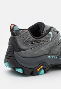 Grau Wanderschuh aus Wildleder und Mesh, mit einer strukturierten Gummisohle mit türkisfarbenen Akzenten und einem sichtbaren GORE-TEX-Label.