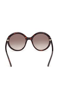 Lunettes de soleil rondes en écaille de tortue avec des verres bruns dégradés et des branches fines, vues de face sur un fond blanc.