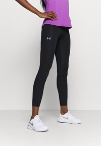 Svarta leggings tillverkade av stretchigt material med en slät yta, med en åtsittande design och en liten grå logotyp på vänster sida.