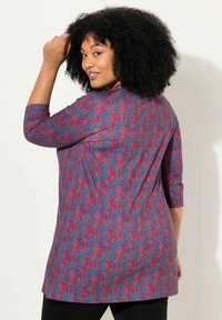 Langermige tuniek met een abstract patroon in blauw, rood en roze. Gemaakt van een zachte stof met een relaxte pasvorm, die onder de heupen valt.