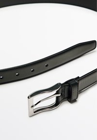 Zwarte leren riem met een glanzende zilveren metalen gesp, met een gladde textuur en zichtbare gaten voor verstelling.