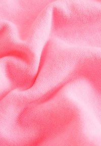 Miękka, różowa dzianina z delikatnymi fałdami i gładką, przytulną fakturą.