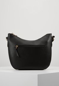 Borsa a spalla in pelle nera con forma curva, chiusura con zip e tasca frontale. Presenta dettagli in metallo dorato e una superficie liscia.
