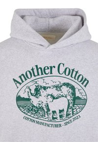 Gray cotton hoodie featuring a green graphic of a sheep and lamb, text reads "Another Cotton" and "Cotton Manufacturer - Since 2023."