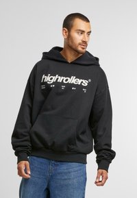 Fekete, puha anyagból készült kapucnis pulóver, kenguru zsebbel. Elöl fehér grafikai szöveg található: "highrollers" és kiegészítő szimbólumok.