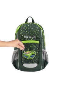 Grüner Rucksack mit geometrischem Muster und neonfarbenen Akzenten. Verfügt über einen Dinosaurier-Patch, eine Reißverschluss-Fronttasche und seitliche Netztaschen.