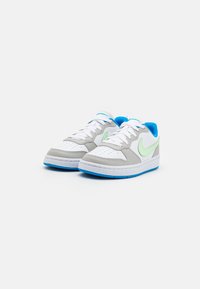 Sneakers featuring a white leather upper with grey accents, light green swoosh logo, and blue detailing on the collar and sole.