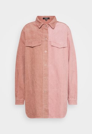 Veste chemise en velours côtelé à manches longues avec boutons-pression, poches poitrine, et design bicolore rose, plus clair à droite et plus foncé à gauche.