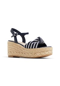 Sandales compensées espadrilles rayées bleu marine et blanches avec un design noué, une bride en cuir à la cheville et une semelle intermédiaire en corde tressée texturée.