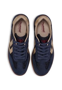 Sneakers med ett mörkblått mockaskinn, beige accenter och tonala mönster. Har en gummisula och platta snören. Klassisk atletisk design.