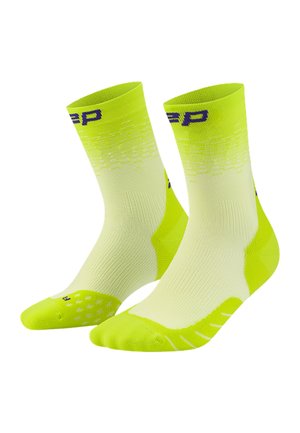 Leuchtend gelb-grüne Sportsocken mit hellem Verlaufsmuster, gerippter Textur und kleinen Logos nahe dem Bund und den Zehenbereichen.