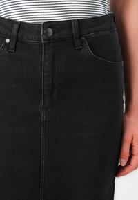 Črna jeans krila z oprijetim krojem, visokim pasom, pet-imi žepi in subtilnim zbledeljem. Opremljena je z gumbom za zapiranje in zanko za pas.