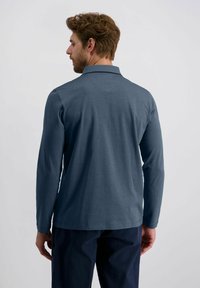 Langärmliges Poloshirt aus dunkelblauem Stoff mit weicher Textur, ausgestattet mit einem Kragen und abgerundetem Saum, von hinten gezeigt.