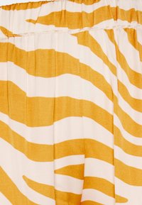 Męskie szorty z elastycznym paskiem, wykonane z lekkiego materiału, w żółto-białe poziome paski. Gładka tekstura i luźny krój.