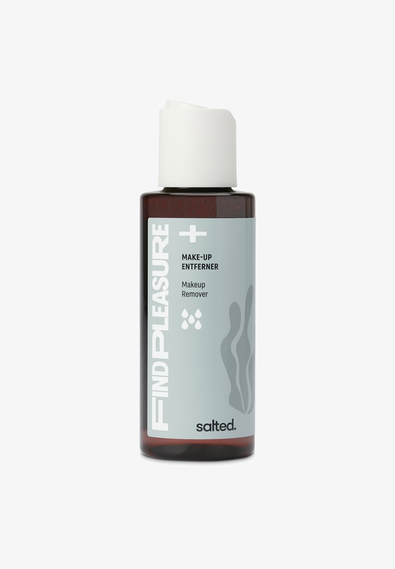 Bruine glazen fles met witte schroefdop; gelabeld "VIND PLEZIER + MAKE-UP VERBETERAAR," bevat make-up remover; lichtgrijze accenten en golvend patroon.