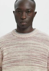 Maglione lavorato a maglia con base color crema chiaro e strisce rosa e grigie. Scollo rotondo e polsini a costine, realizzato con filato testurizzato.