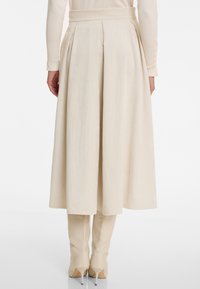 Cream ribbed midi skirt with pleats at the waist, paired with form-fitting beige knee-high boots. Skirt has a smooth texture.