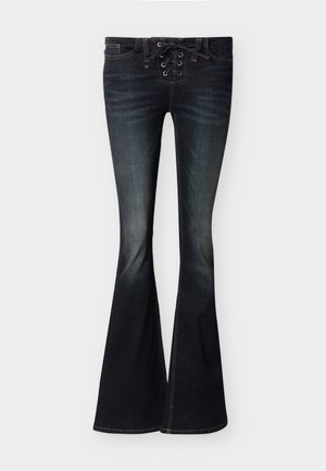 Τζιν με σκουρόχρωμο ξέβγαλμα και φαρδιά καμπάνα, με δέσιμο στο μπροστινό μέρος και διακριτική ξεθώριαση στους μηρούς και τα γόνατα, απλωμένα σε επίπεδη επιφάνεια.