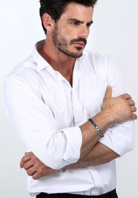 Herrars blå pärlarmband har en blandning av marinblå och silvertoner, trätt på en flexibel tråd. Designen är stilren och minimalistisk.